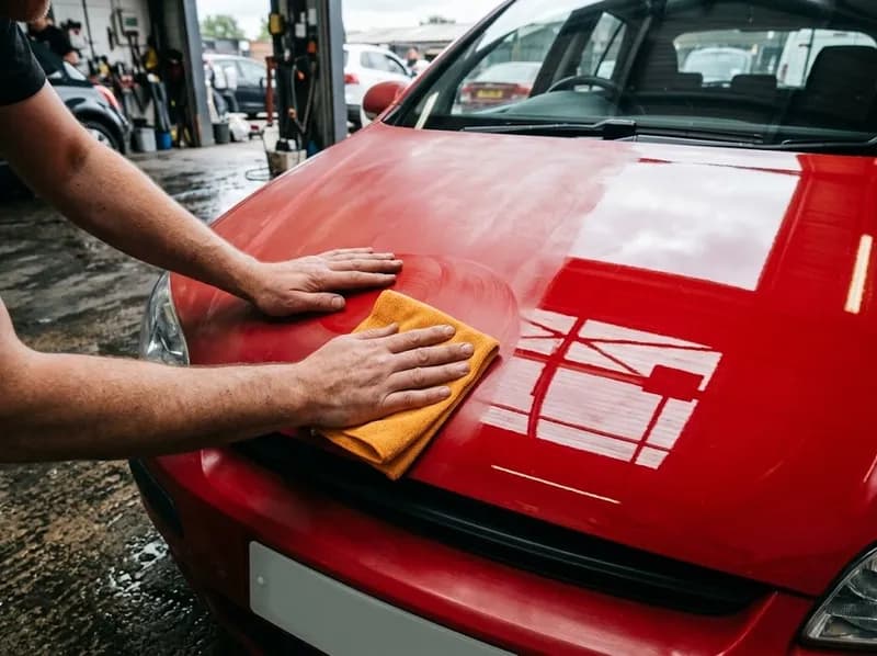 Aplicação e polimento de cera no capô de um carro